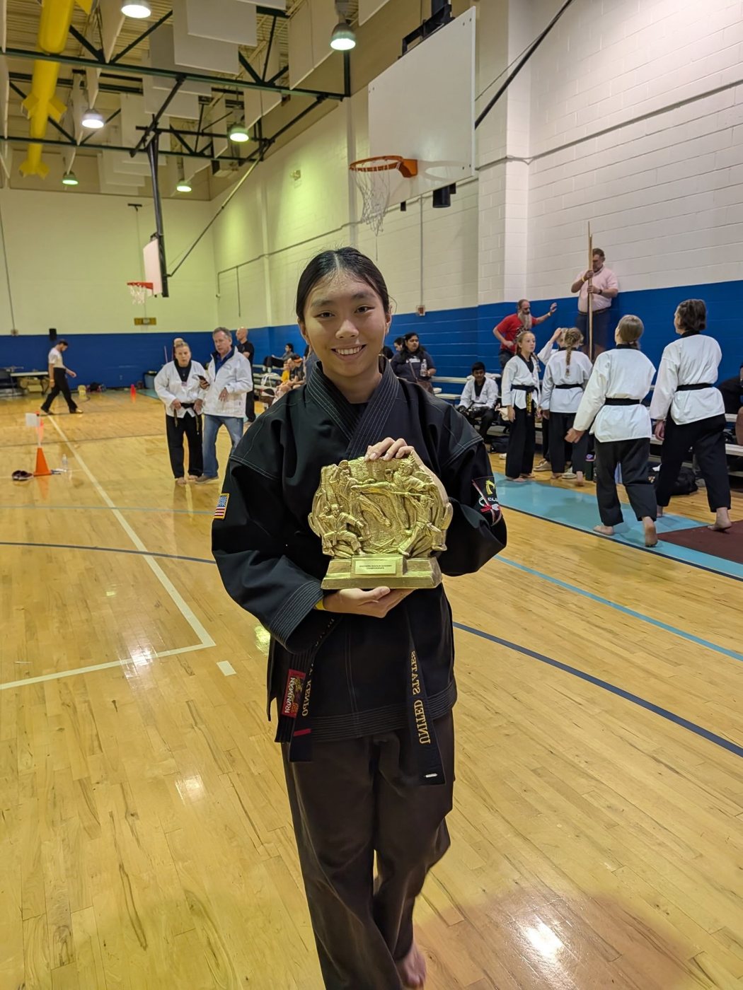 Elizabeth Lau holding a tournament trophy at a martial arts competition